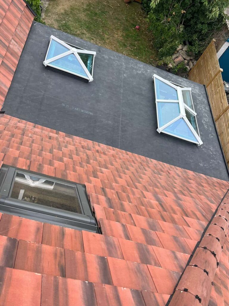This is a photo taken from the roof ridge looking down a tiled pitched roof on to a flat roof. Works carried out by Ilkeston Roofing Repairs