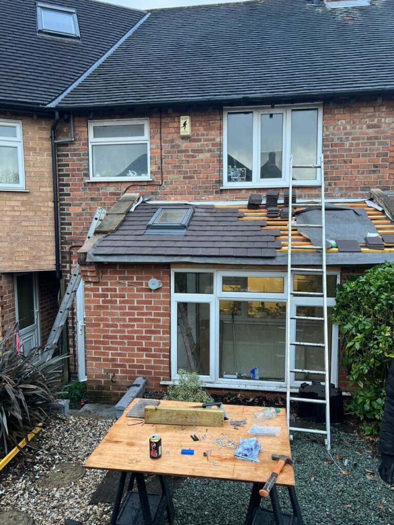 This is a photo of a roof extension that is having new roof tiles installed. This is a photo taken from the roof ridge looking down a tiled pitched roof on to a flat roof. Works carried out by Ilkeston Roofing Repairs